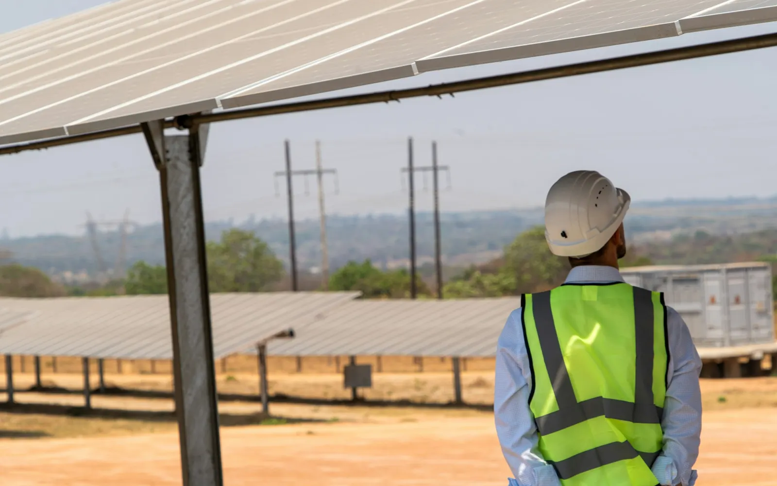 Fachkraft mit Schutzhelm und Warnweste unter Photovoltaikmodulen