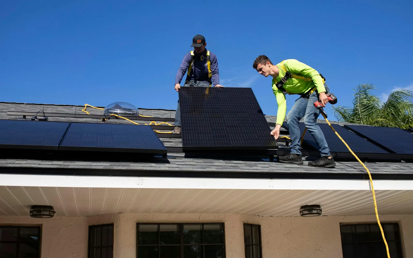 Handwerker bei Arbeiten an Photovoltaikmodulen auf einem Hausdach